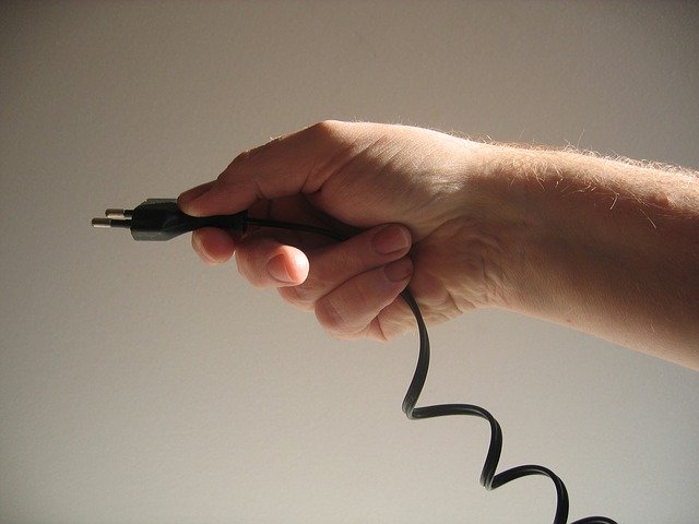 Človek drží v ruke čierny elektrický kábel